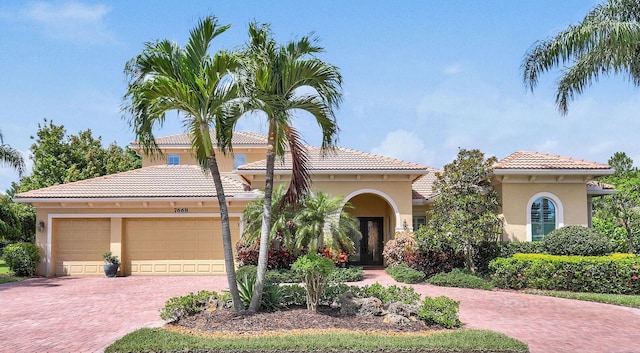 7668 SE Laque Cir, Stuart, FL 34997 - mediterranean / spanish-style house featuring decorative driveway, stucco siding, an attached garage, and a tiled roof