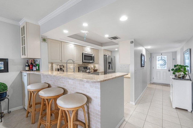20 NE Plantation Rd Unit 203, Stuart, FL 34996 - kitchen featuring stainless steel appliances, light tile patterned flooring, baseboards, a breakfast bar, and crown molding