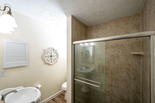 3056 SE Morningside Blvd, Port Saint Lucie, FL 34952 - bathroom with a stall shower, a textured ceiling, toilet, wood finished floors, and a sink