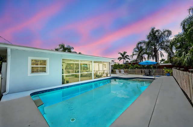 3056 SE Morningside Blvd, Port Saint Lucie, FL 34952 - pool at dusk featuring a sunroom and a patio area