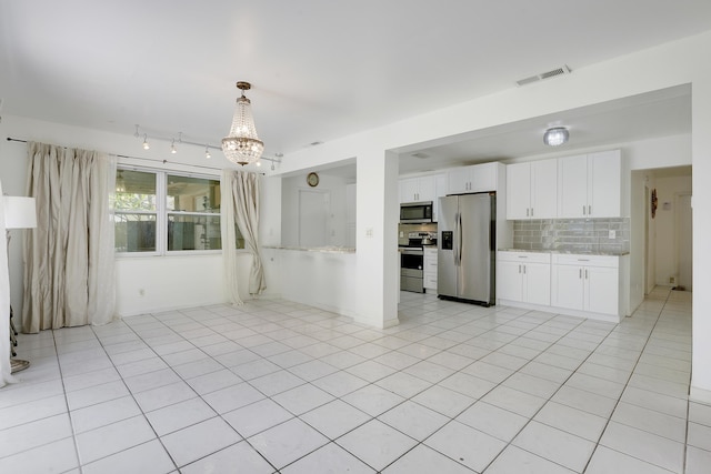unfurnished room featuring a chandelier, light tile patterned flooring, and track lighting