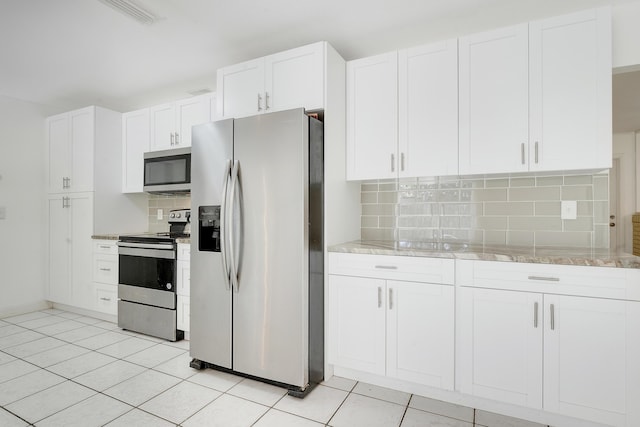 kitchen with appliances with stainless steel finishes, tasteful backsplash, light stone countertops, and white cabinets