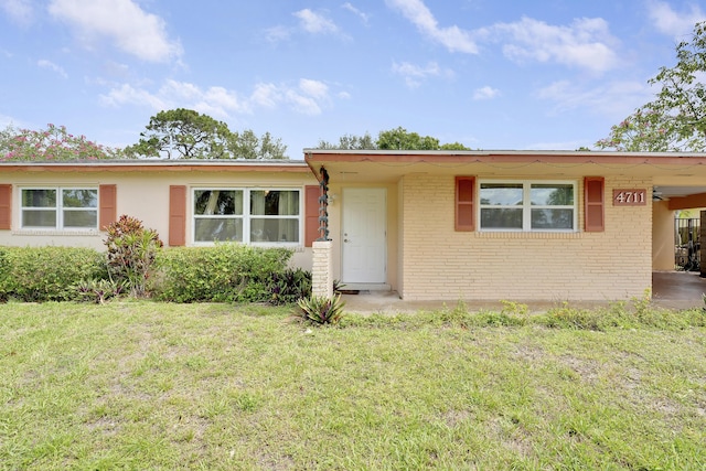 single story home featuring a front yard, brick siding, and an attached carport