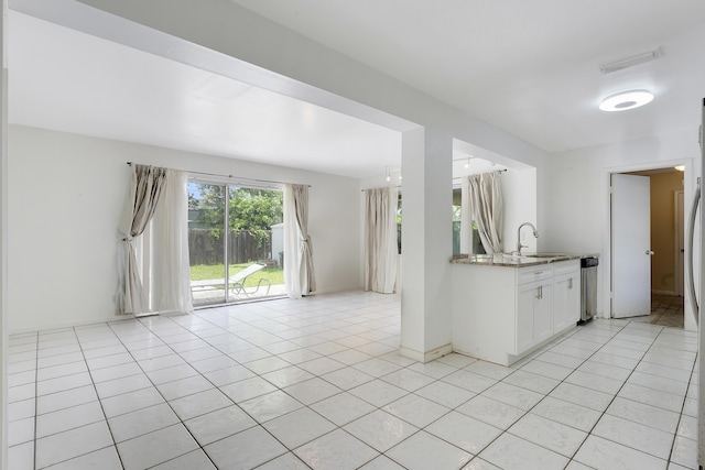 kitchen with a sink, white cabinets, light tile patterned floors, and dishwasher
