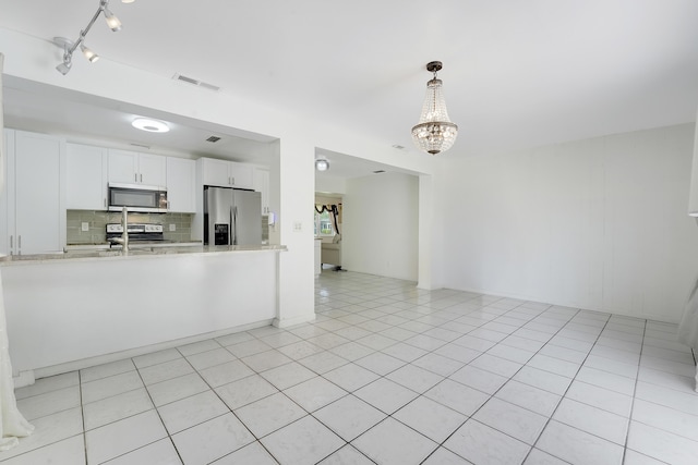 kitchen featuring stainless steel appliances, backsplash, a chandelier, white cabinetry, and hanging light fixtures