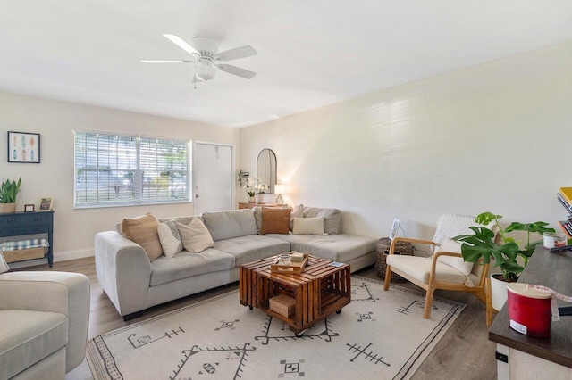 living area with light wood-style floors, ceiling fan, and baseboards