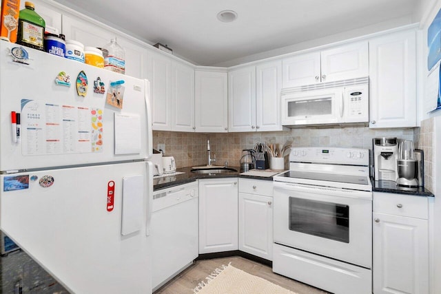 kitchen with white appliances, a sink, white cabinetry, and tasteful backsplash