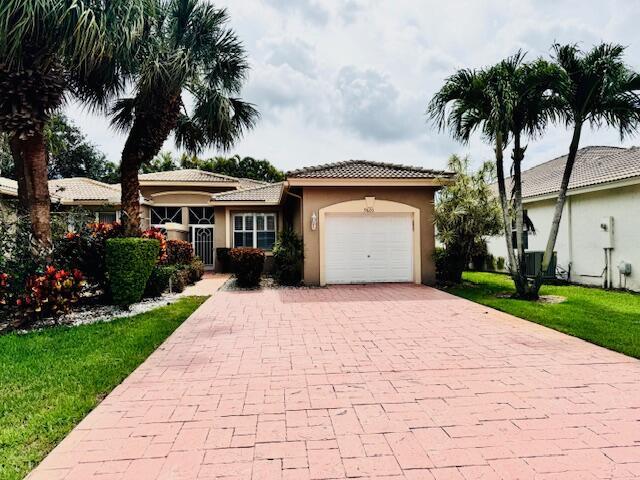 9620 Crescent View Dr N, Boynton Beach, FL 33437 - ranch-style home with decorative driveway, a garage, stucco siding, a tiled roof, and a front yard