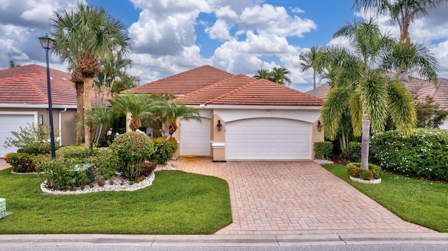 4498 Hazleton Ln, Lake Worth, FL 33449 - mediterranean / spanish house featuring a front lawn, a garage, decorative driveway, stucco siding, and a tiled roof