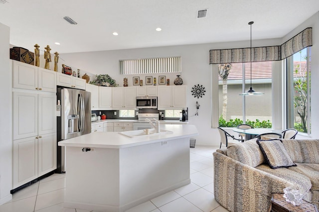 4498 Hazleton Ln, Lake Worth, FL 33449 - kitchen featuring stainless steel appliances, a sink, light countertops, light tile patterned floors, and white cabinetry
