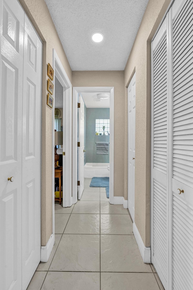 6738 Moonlit Dr, Delray Beach, FL 33446 - hallway featuring a textured ceiling, light tile patterned floors, and baseboards