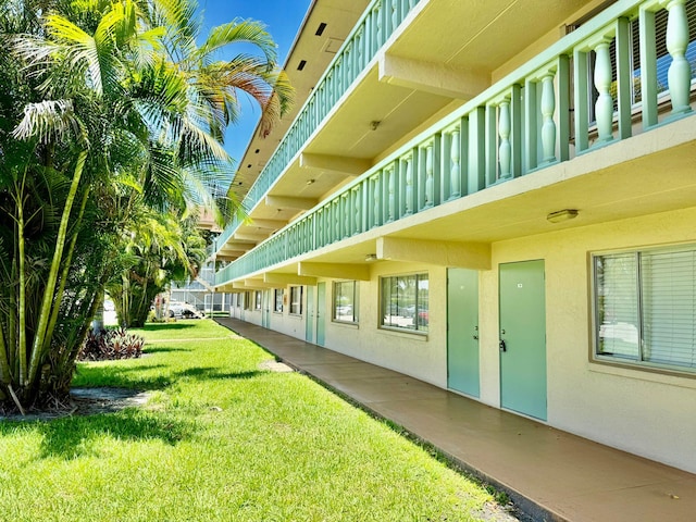 view of green lawn featuring a balcony