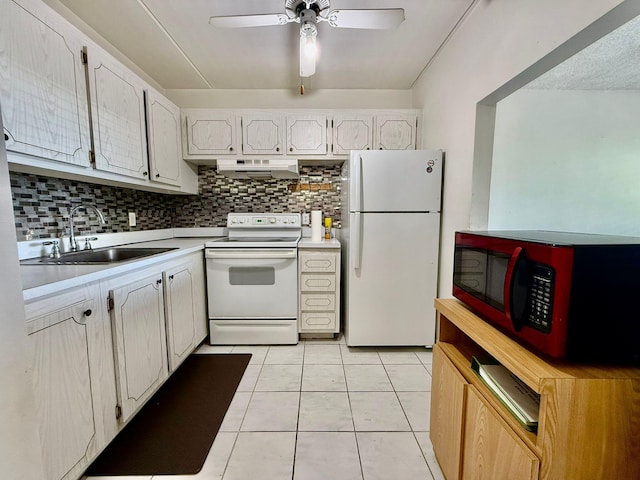 kitchen with white appliances, a sink, under cabinet range hood, light countertops, and tasteful backsplash