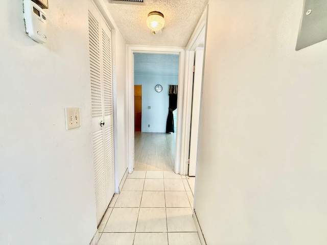 corridor with light tile patterned floors and a textured ceiling