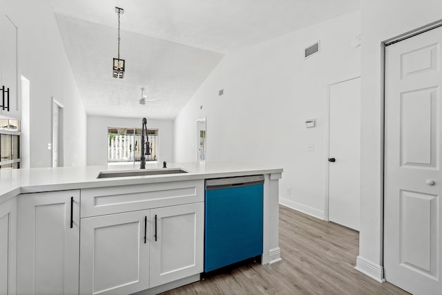 kitchen featuring dishwasher, a sink, light wood-type flooring, light countertops, and lofted ceiling