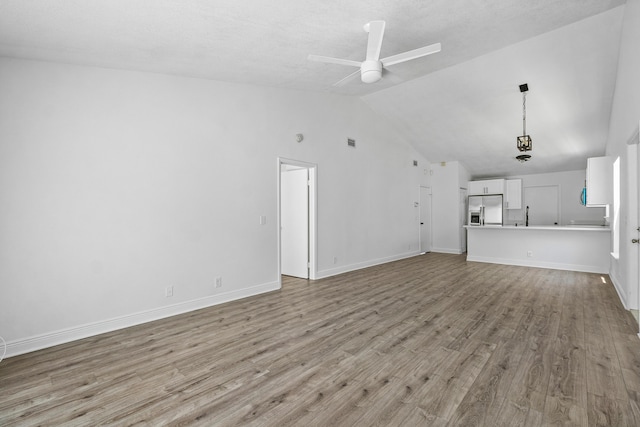unfurnished living room with lofted ceiling, light wood-style flooring, a ceiling fan, and baseboards