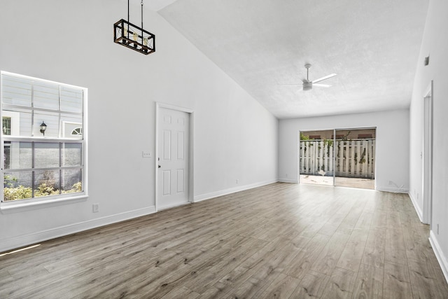 unfurnished living room featuring wood finished floors, ceiling fan, high vaulted ceiling, and baseboards