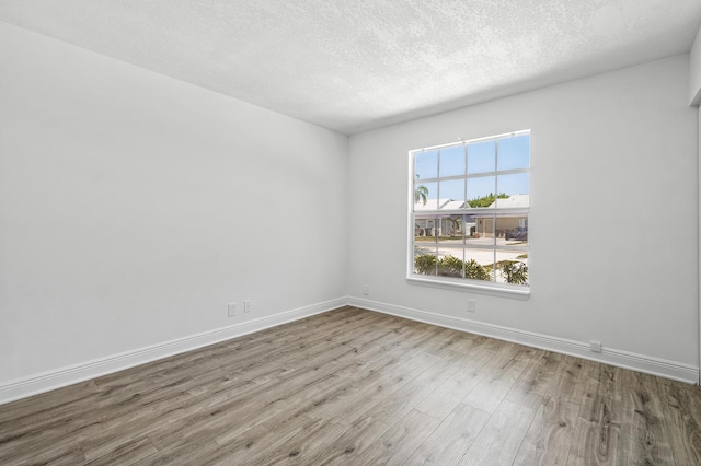 empty room with wood finished floors, baseboards, and a textured ceiling