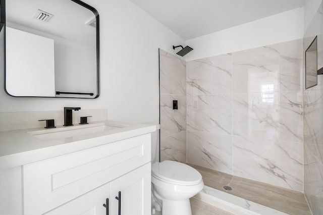 full bathroom with a marble finish shower, vanity, and toilet