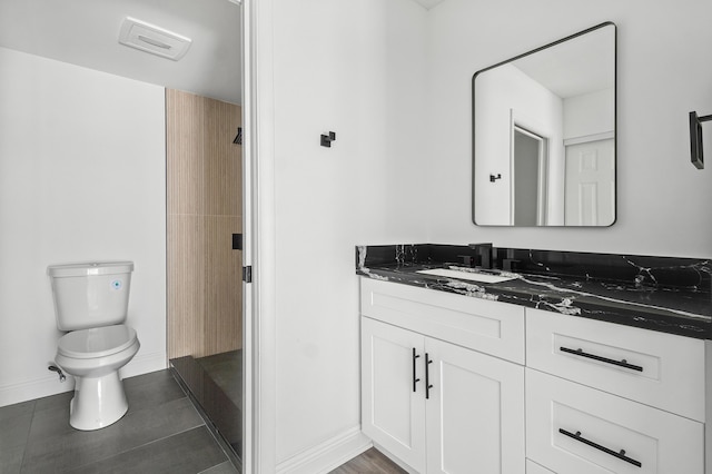 bathroom featuring toilet, vanity, and baseboards