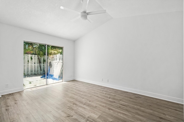 empty room with vaulted ceiling, wood finished floors, a ceiling fan, and baseboards