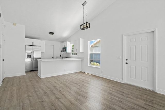 kitchen featuring appliances with stainless steel finishes, light countertops, high vaulted ceiling, white cabinets, and light wood-type flooring
