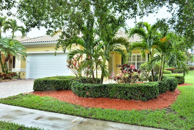 view of side of home featuring an attached garage, stucco siding, decorative driveway, and a tiled roof