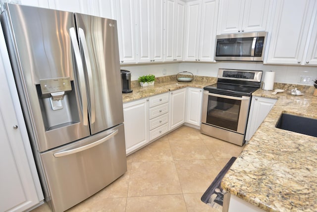 kitchen featuring stainless steel appliances, white cabinetry, light tile patterned flooring, and light stone countertops