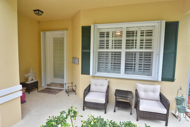 view of exterior entry featuring stucco siding and a patio area