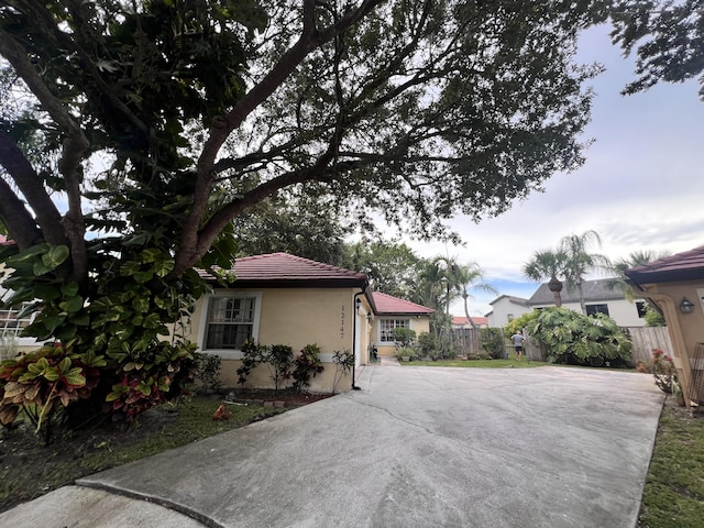 12147 Cuddington Ct, Wellington, FL 33414 - view of side of property featuring concrete driveway, a tile roof, fence, and stucco siding