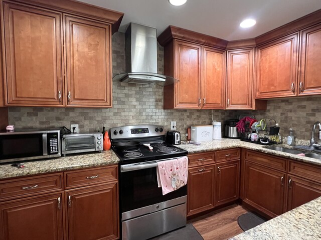 12147 Cuddington Ct, Wellington, FL 33414 - kitchen with appliances with stainless steel finishes, wall chimney exhaust hood, a sink, backsplash, and light wood-style flooring