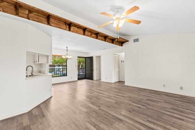 3 Via De Casas Sur Unit 204, Boynton Beach, FL 33426 - unfurnished living room featuring a chandelier, wood finished floors, baseboards, a ceiling fan, and a sink