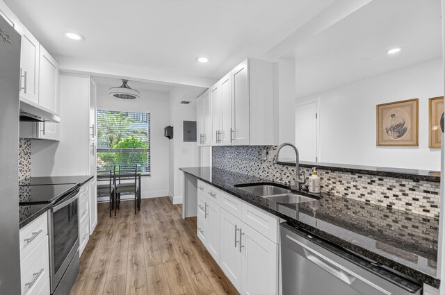 830 Greensward Ct Unit 107-H, Delray Beach, FL 33445 - kitchen with stainless steel appliances, dark stone counters, backsplash, light wood-style flooring, and white cabinetry