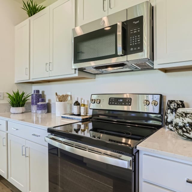 555 SE Rivergrass St, Port Saint Lucie, FL 34984 - kitchen with appliances with stainless steel finishes, light stone counters, and white cabinets