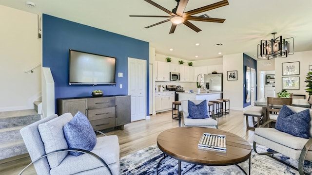 555 SE Rivergrass St, Port Saint Lucie, FL 34984 - living area featuring light wood-style flooring, a ceiling fan, stairway, a chandelier, and baseboards