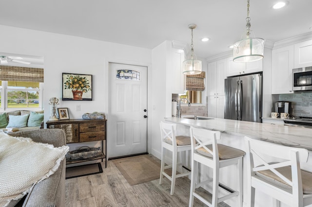 1045 Circle Ter E Unit D, Delray Beach, FL 33445 - kitchen with appliances with stainless steel finishes, a sink, light wood-type flooring, tasteful backsplash, and white cabinets