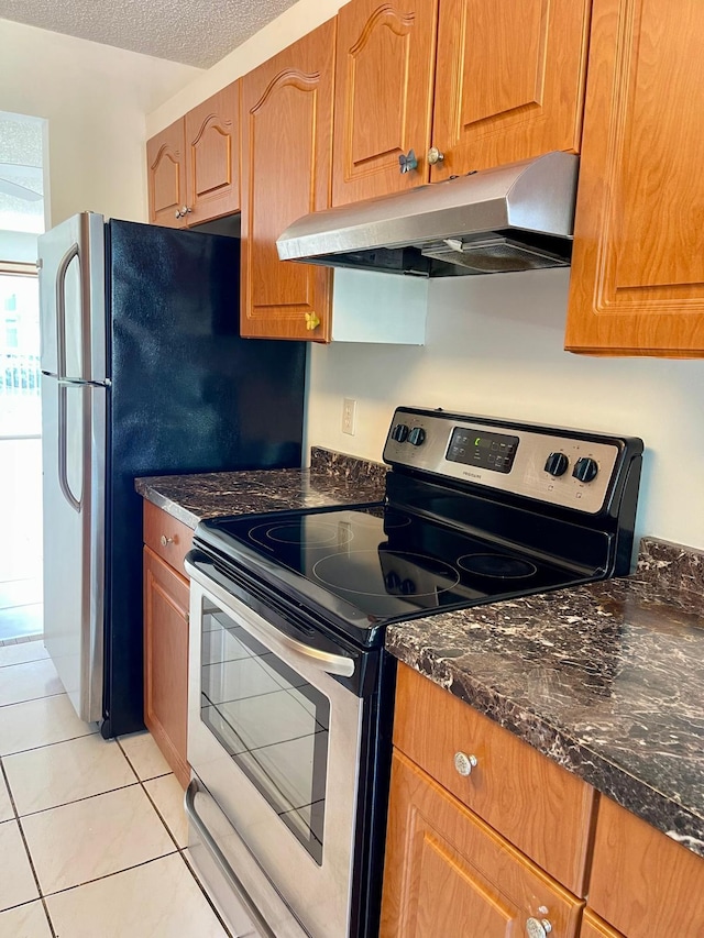 650 SW 124th Ter Unit 202P, Pembroke Pines, FL 33027 - kitchen featuring electric stove, under cabinet range hood, light tile patterned floors, dark stone counters, and brown cabinets