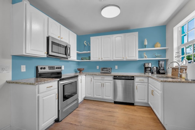 301 SW 1st Ave, Delray Beach, FL 33444 - kitchen featuring stainless steel appliances, open shelves, a sink, light stone counters, and white cabinets