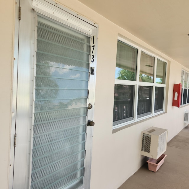 173 Kent J, West Palm Beach, FL 33417 - property entrance featuring stucco siding and a wall unit AC