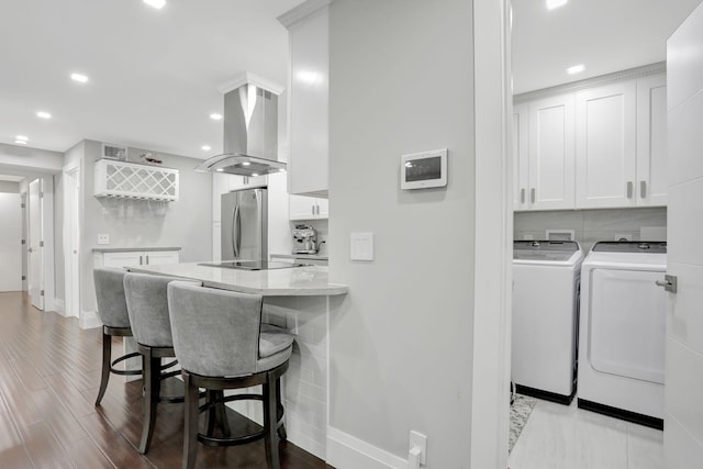 545 Trace Cir Unit 106, Deerfield Beach, FL 33441 - kitchen with washer and clothes dryer, island range hood, freestanding refrigerator, a kitchen bar, and baseboards