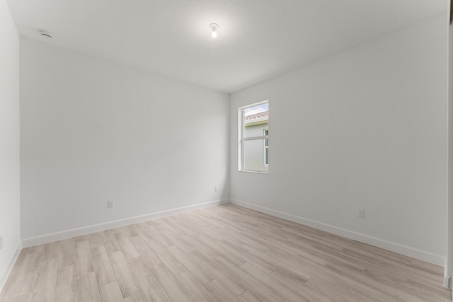 unfurnished room with light wood-style flooring, baseboards, and a smoke detector