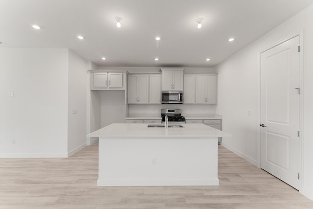 kitchen featuring stainless steel appliances, a center island with sink, light countertops, baseboards, and recessed lighting