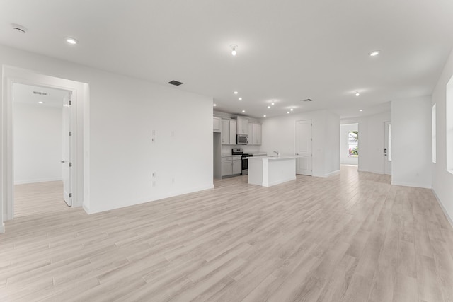 unfurnished living room with light wood-type flooring, recessed lighting, and baseboards