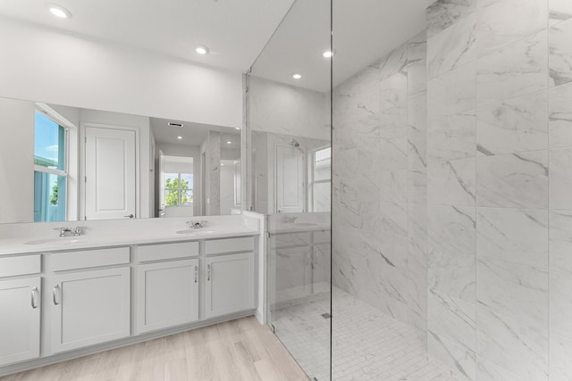 bathroom featuring double vanity, a marble finish shower, recessed lighting, and wood finished floors