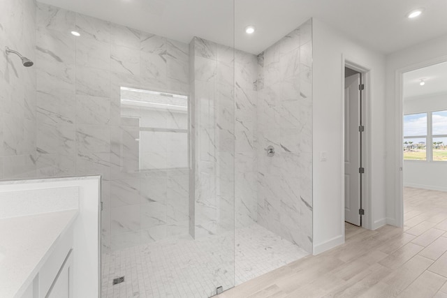 bathroom with recessed lighting, a marble finish shower, wood finished floors, and baseboards