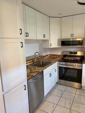 3566 N University Dr Unit F-5, Coral Springs, FL 33065 - kitchen featuring stainless steel appliances, white cabinets, a sink, and dark countertops