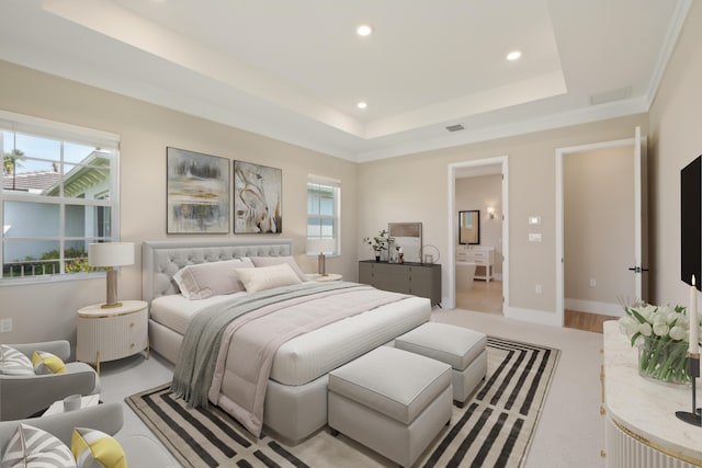 bedroom featuring a raised ceiling, recessed lighting, and ensuite bath