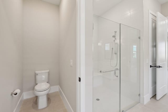 bathroom featuring a stall shower, toilet, baseboards, and tile patterned floors