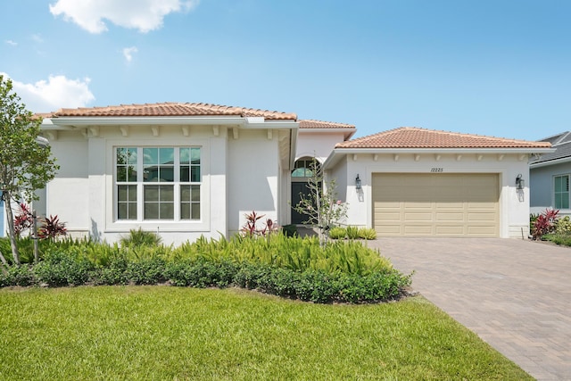 mediterranean / spanish house with stucco siding, a garage, decorative driveway, and a front yard