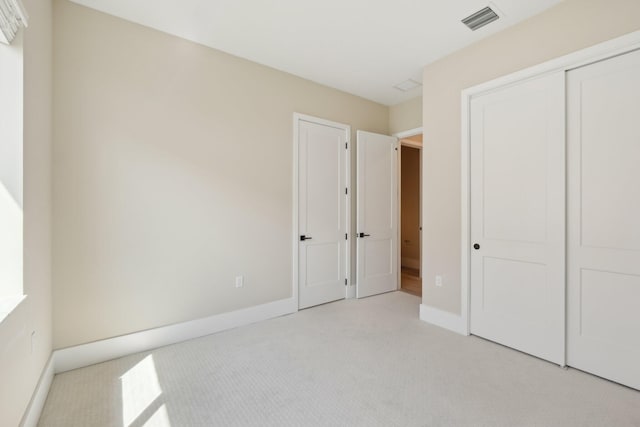 unfurnished bedroom featuring light colored carpet, baseboards, and a closet